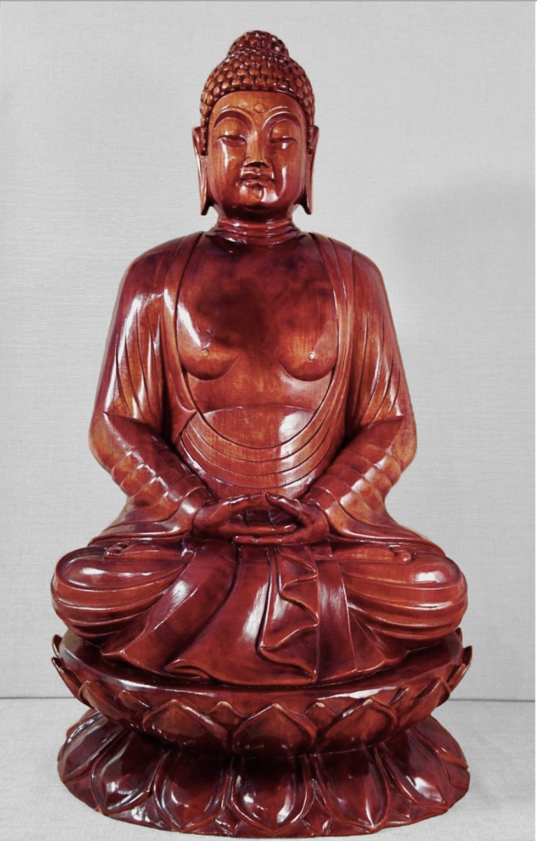 Imagen de una escultura en madera de Buda sentado sobre una flor de loto.